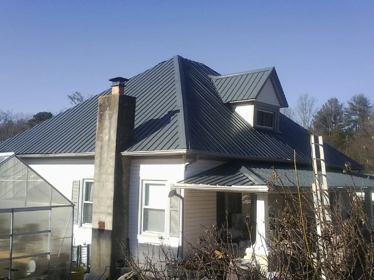 Dark blue standing seam metal roof on a white farmhouse with dormer — Slate & Tile Roof Repair by Roofing Brothers in Glenmoore