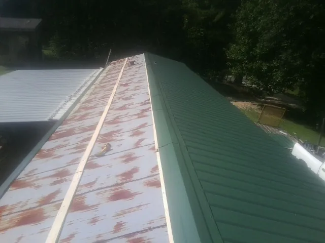 Old rusted panels beside newly installed green metal roofing — Wind Damage Roof Repair by Roofing Brothers in Glenmoore