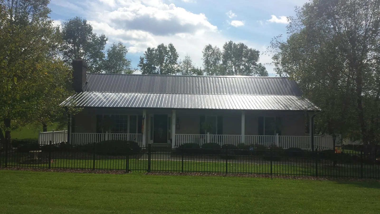 Gray metal roof on a brick ranch with a full width front porch — Gutter Guard Installation work by our crew in Glenmoore