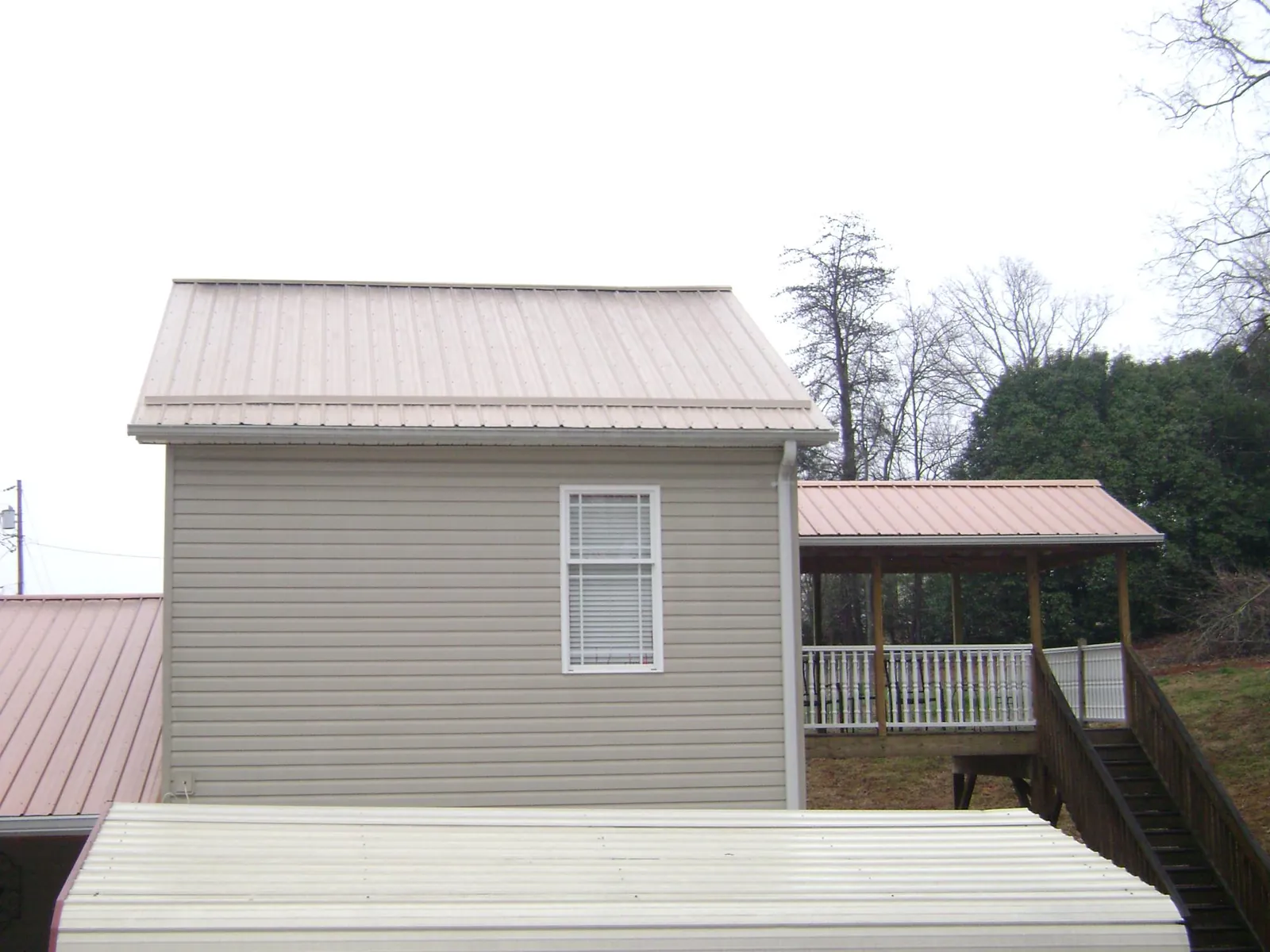 Tan metal roofs on a two story addition and attached porch, from a Roof Replacement job in Glenmoore