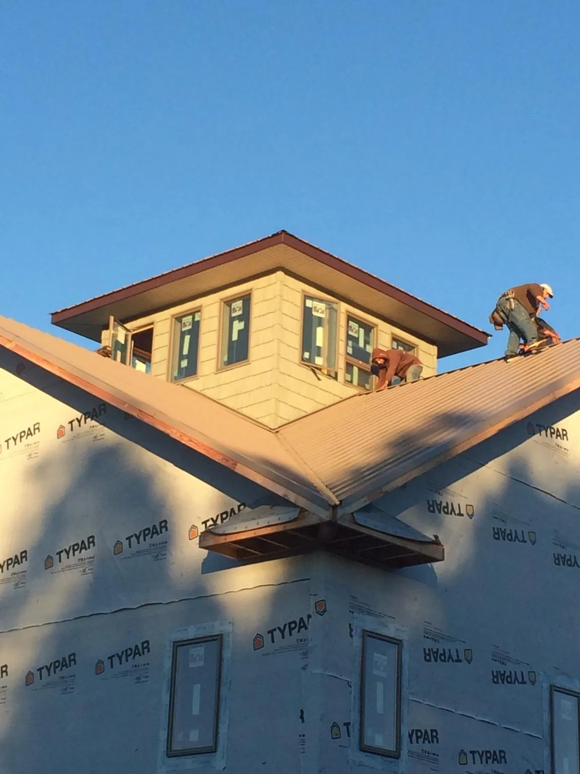 Roofers working around a rooftop cupola on a new metal roof at sunset — Roof Waterproofing in Glenmoore by Roofing Brothers